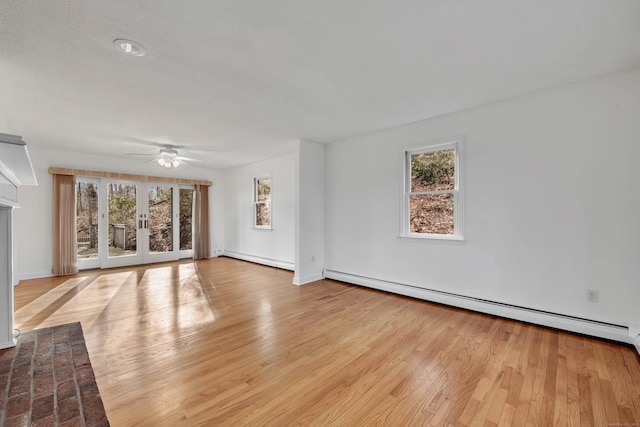 unfurnished living room featuring a wealth of natural light, french doors, light hardwood / wood-style flooring, and baseboard heating