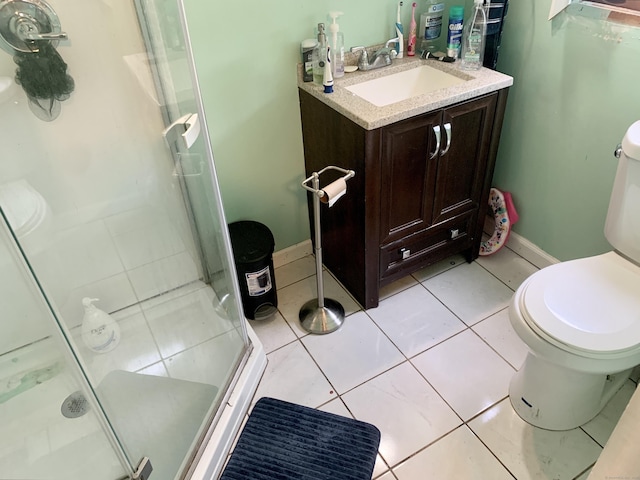 bathroom with tile patterned floors, vanity, a shower with shower door, and toilet