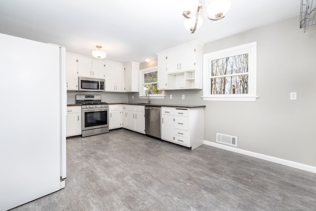 kitchen featuring white cabinets, sink, appliances with stainless steel finishes, a notable chandelier, and light hardwood / wood-style floors