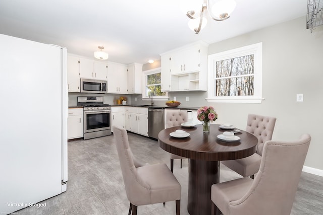 kitchen with appliances with stainless steel finishes, an inviting chandelier, white cabinetry, and sink