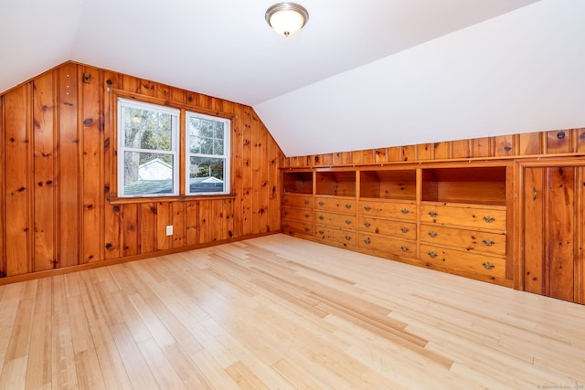 additional living space featuring wood walls, light hardwood / wood-style flooring, and lofted ceiling