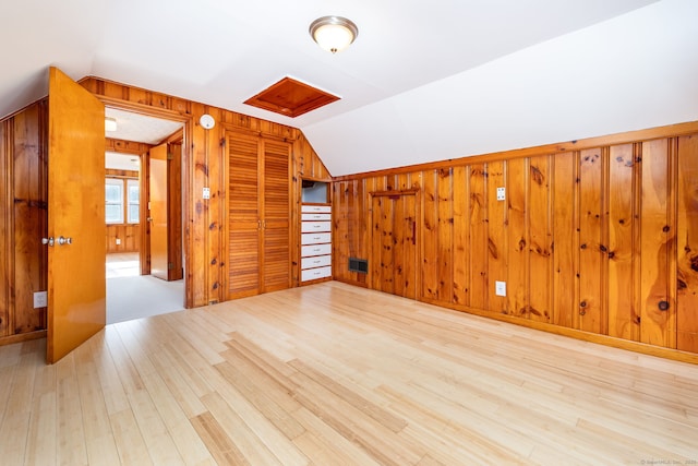 additional living space with light hardwood / wood-style floors, vaulted ceiling, and wood walls