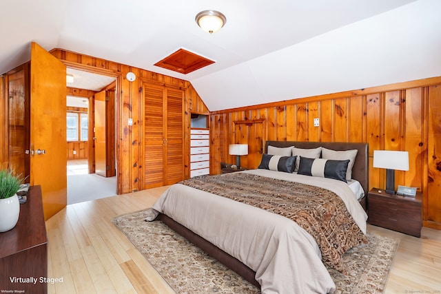 bedroom featuring light hardwood / wood-style floors, lofted ceiling, and wooden walls