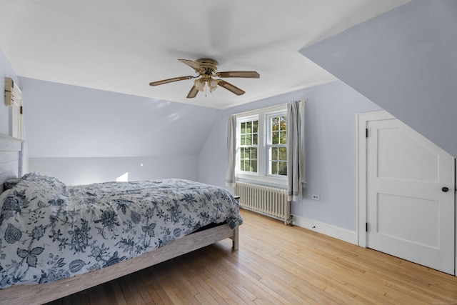 bedroom with ceiling fan, radiator heating unit, vaulted ceiling, and light wood-type flooring