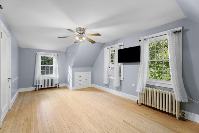 additional living space featuring a wealth of natural light, light wood-type flooring, lofted ceiling, and radiator