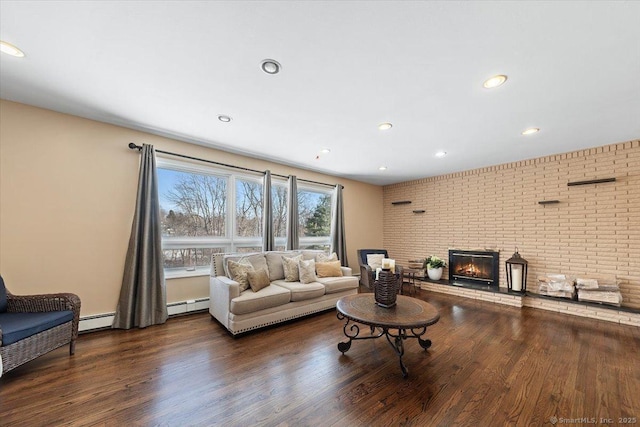 living room with dark wood-type flooring, brick wall, and a baseboard heating unit