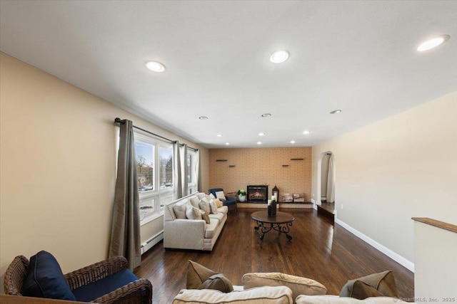 living room featuring a baseboard radiator, dark hardwood / wood-style floors, and a brick fireplace