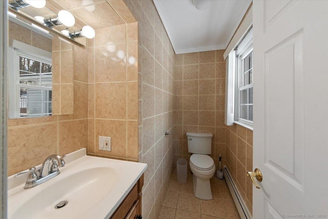 bathroom with baseboard heating, crown molding, toilet, vanity, and tile walls