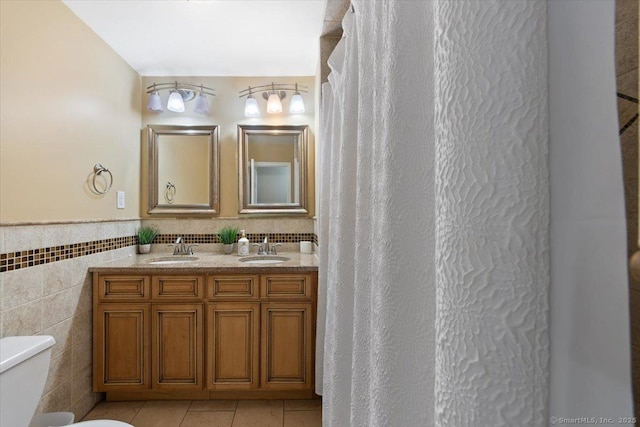 bathroom with tile patterned flooring, vanity, tile walls, and toilet