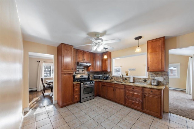 kitchen featuring decorative light fixtures, gas stove, sink, and tasteful backsplash