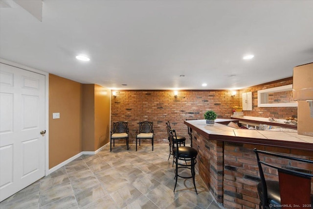 bar with tile countertops and brick wall