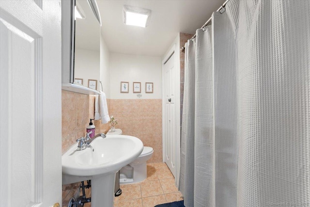 bathroom featuring tile patterned flooring, toilet, and tile walls