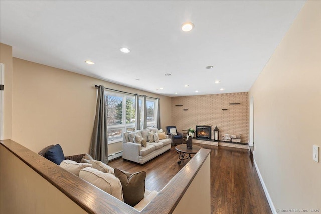 living room featuring dark wood-type flooring, a baseboard radiator, and a brick fireplace