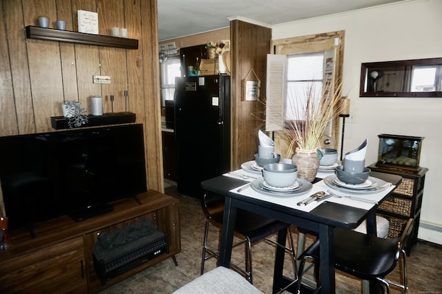 dining space with wooden walls, ornamental molding, and a healthy amount of sunlight