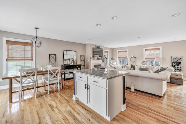 kitchen featuring a center island, dark stone counters, pendant lighting, light hardwood / wood-style floors, and white cabinets