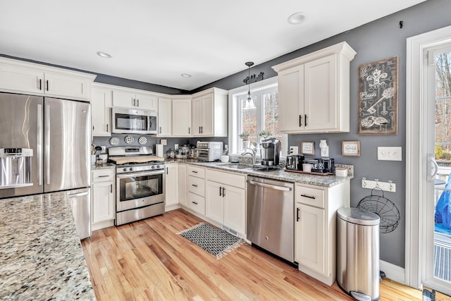 kitchen featuring hanging light fixtures, white cabinets, and stainless steel appliances