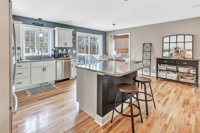 kitchen featuring appliances with stainless steel finishes, a center island, white cabinetry, and hanging light fixtures