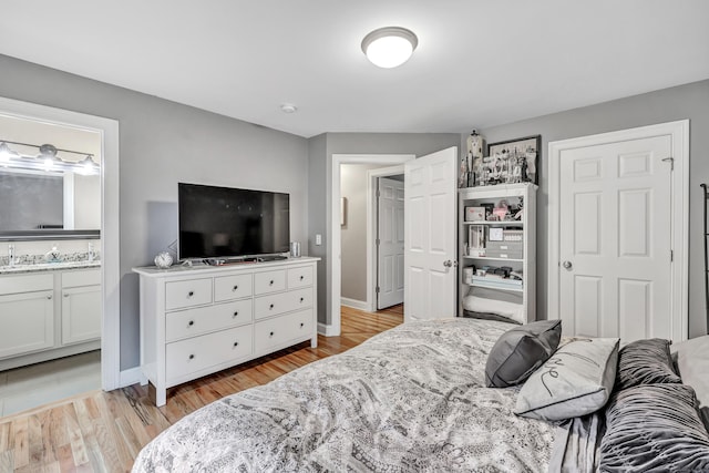 bedroom featuring ensuite bath and light hardwood / wood-style flooring