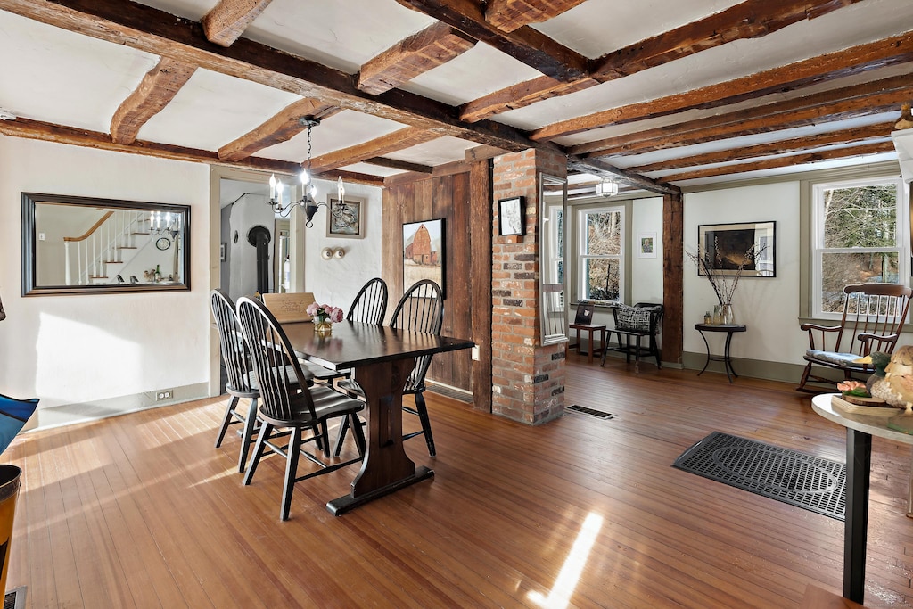 dining area with beamed ceiling, dark hardwood / wood-style floors, coffered ceiling, and an inviting chandelier