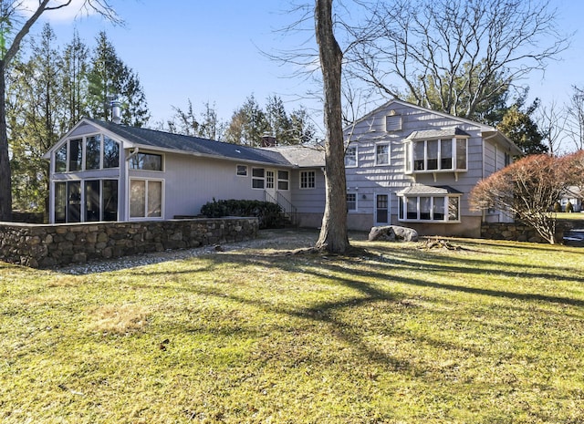 back of house with a sunroom and a lawn