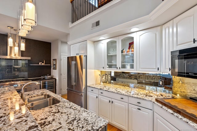 kitchen with high end refrigerator, white cabinetry, pendant lighting, and sink