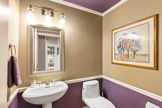 bathroom with toilet, ornamental molding, and sink