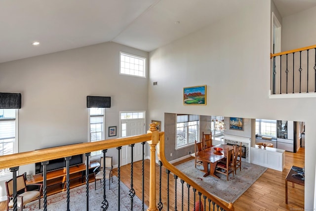 interior space featuring light wood-type flooring, high vaulted ceiling, a stone fireplace, and a healthy amount of sunlight