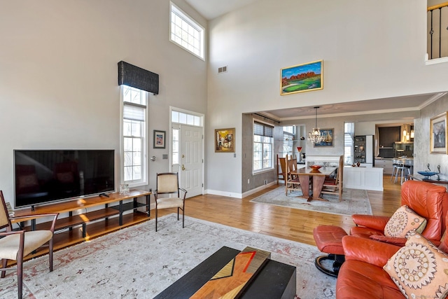 living room featuring a high ceiling, light wood-type flooring, and crown molding