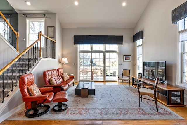 living room featuring high vaulted ceiling, light hardwood / wood-style floors, and a wealth of natural light