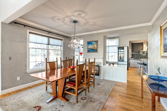 dining space featuring light wood-type flooring, crown molding, and a chandelier