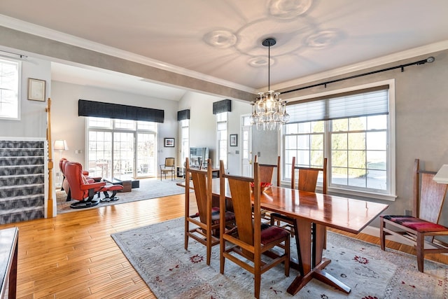 dining room with hardwood / wood-style flooring, a notable chandelier, and crown molding