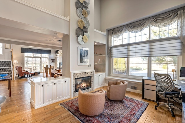 home office featuring a high ceiling, light hardwood / wood-style floors, and a premium fireplace