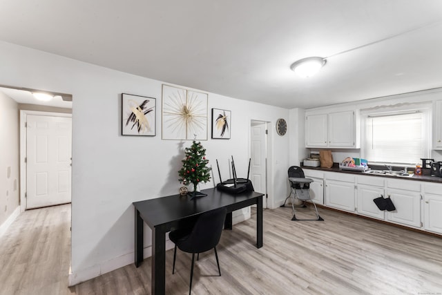 office with light wood-type flooring and sink