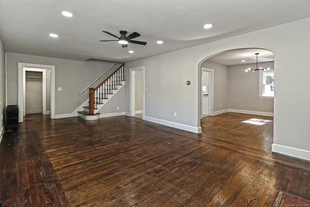 unfurnished living room featuring dark hardwood / wood-style flooring and ceiling fan with notable chandelier