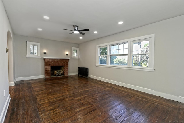 unfurnished living room featuring ceiling fan, radiator heating unit, dark hardwood / wood-style flooring, and a fireplace