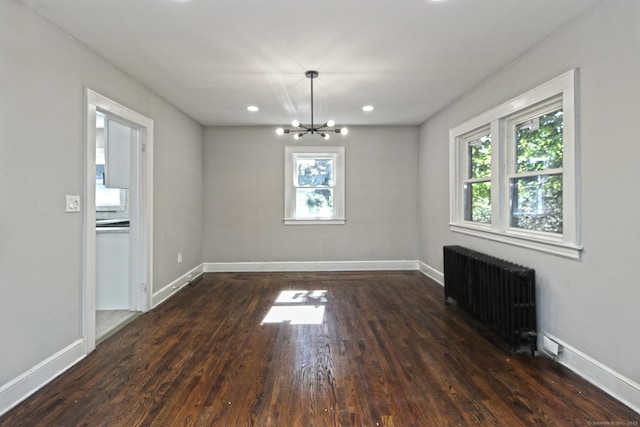 unfurnished dining area featuring dark hardwood / wood-style floors, radiator, and an inviting chandelier