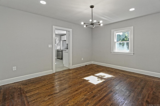 unfurnished room featuring dark wood-type flooring and a notable chandelier