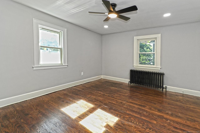 unfurnished room featuring ceiling fan, dark wood-type flooring, and radiator heating unit