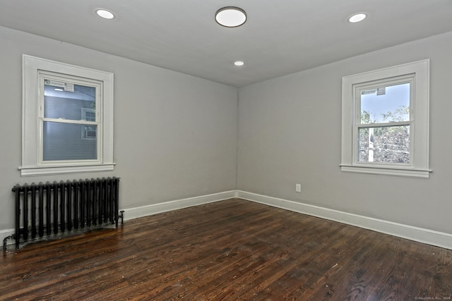 unfurnished room featuring dark hardwood / wood-style flooring and radiator heating unit