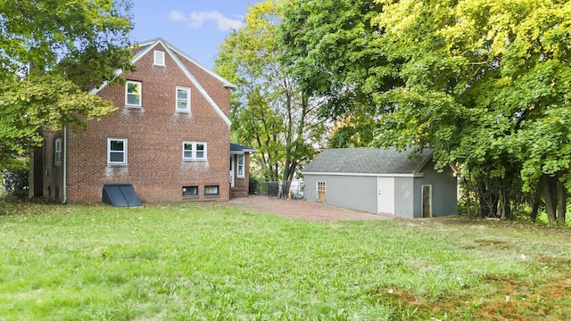 back of property with a yard and an outdoor structure