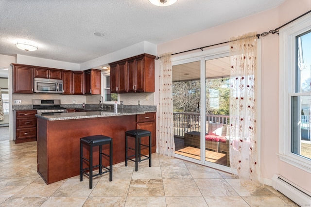 16 Snow Rdg S, Middletown, CT 06457 - kitchen with a breakfast bar, a textured ceiling, dark stone counters, stainless steel appliances, and a baseboard radiator
