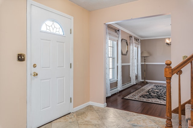 foyer featuring baseboards, crown molding, stairway, and a notable chandelier