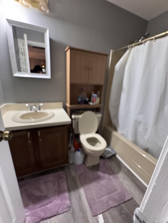 full bathroom featuring hardwood / wood-style floors, vanity, shower / bath combination with curtain, and toilet