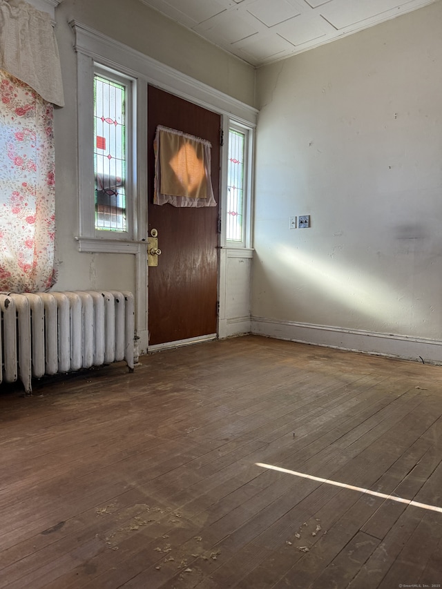 foyer entrance with a healthy amount of sunlight, radiator heating unit, and hardwood / wood-style floors