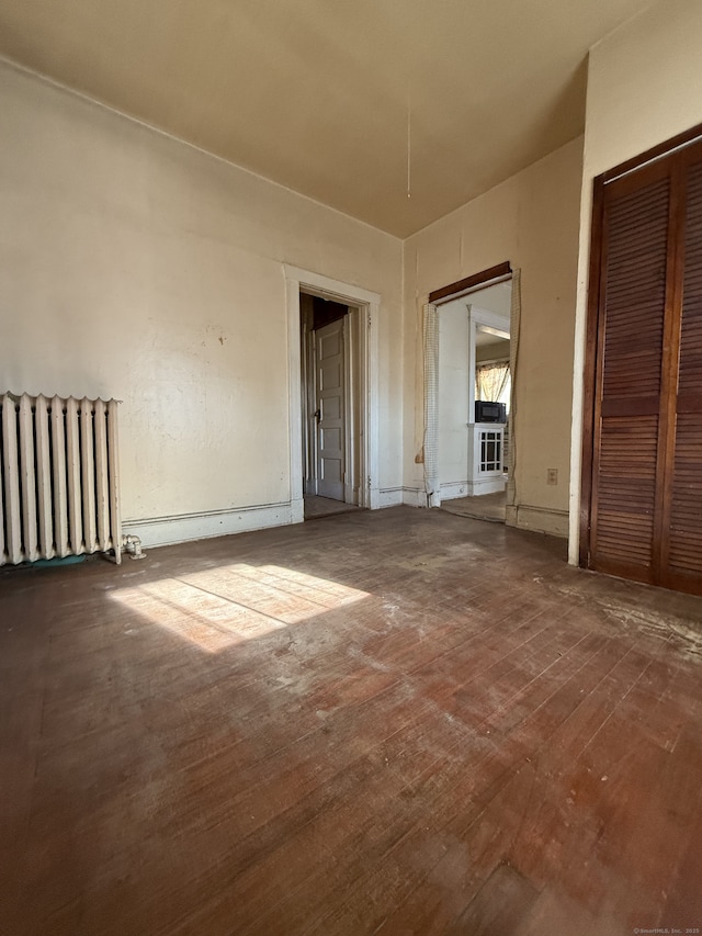 unfurnished bedroom with dark hardwood / wood-style flooring and radiator