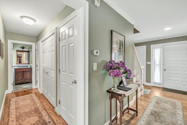 foyer entrance with light hardwood / wood-style floors and crown molding