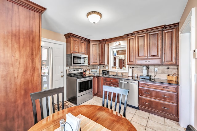 kitchen with dark stone countertops, light tile patterned floors, sink, and appliances with stainless steel finishes