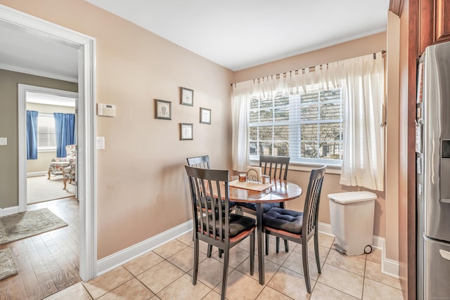 dining space with light tile patterned floors and ornamental molding