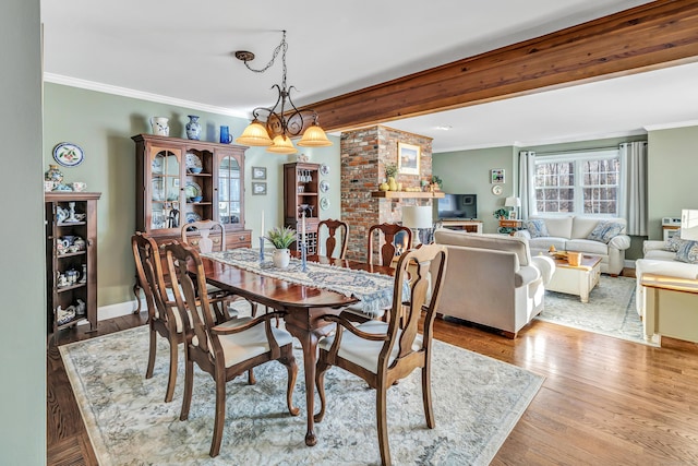 dining space featuring beam ceiling, crown molding, light hardwood / wood-style flooring, and an inviting chandelier