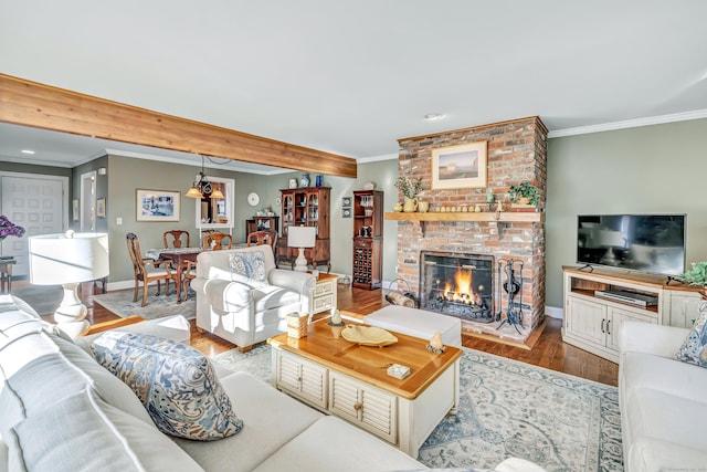 living room with beam ceiling, light wood-type flooring, ornamental molding, and a brick fireplace